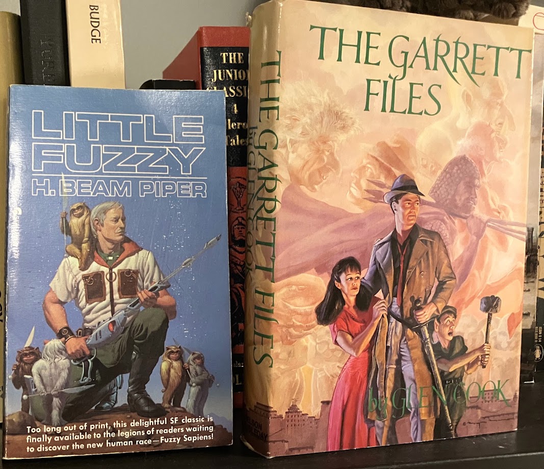 paperback copy of Little Fuzzy by H. Beam Piper and a hardcover edition of The Garrett Files by Glen Cook